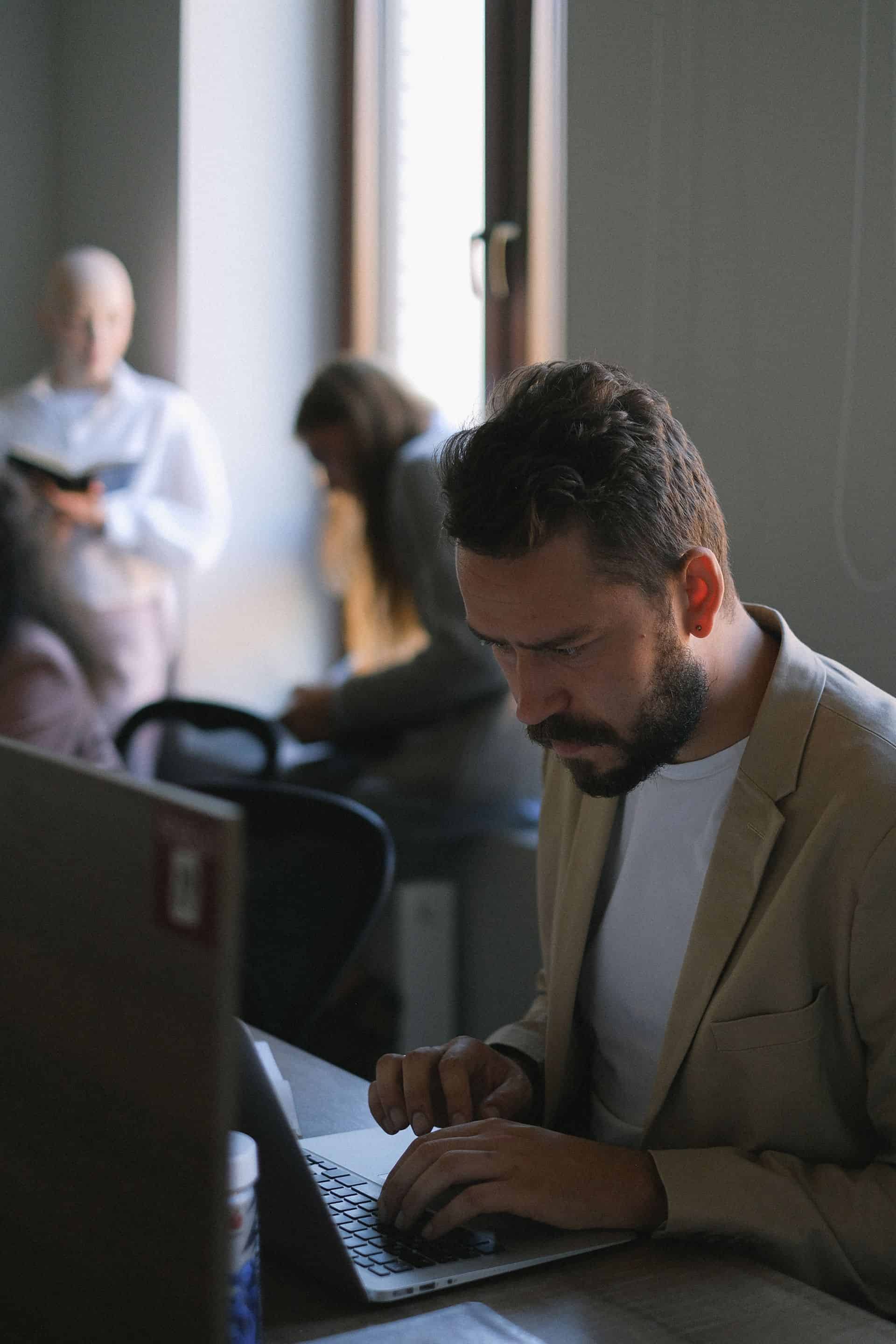 Mężczyzna pracujący na laptopie przy biurku z zachowaniem zasad ergonomii.