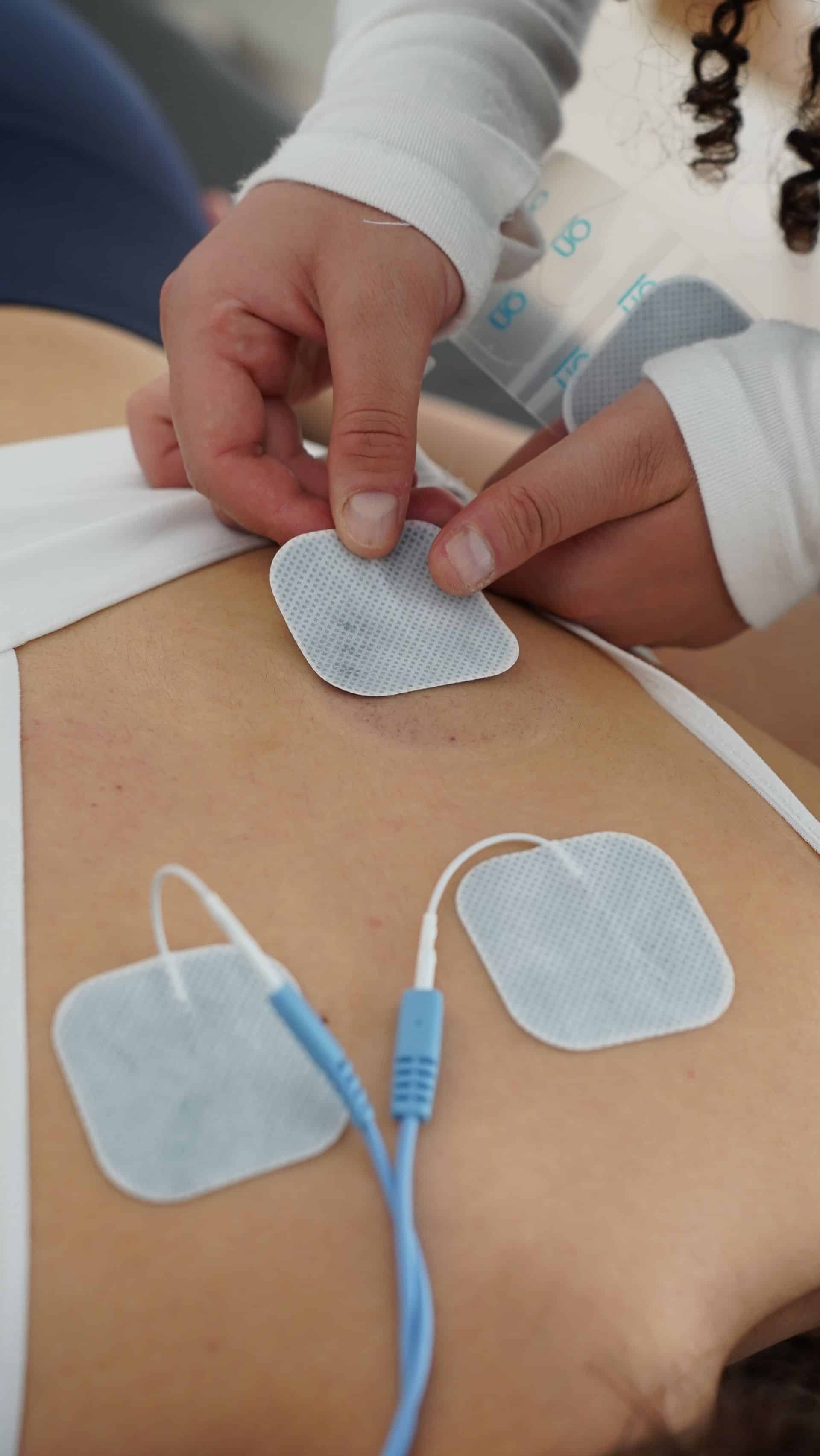Aparatura do terapii energotonowej HiToP podłączona do leżącego na łóżku rehabilitacyjnym pacjenta, z widocznymi elektrodami na ciele.