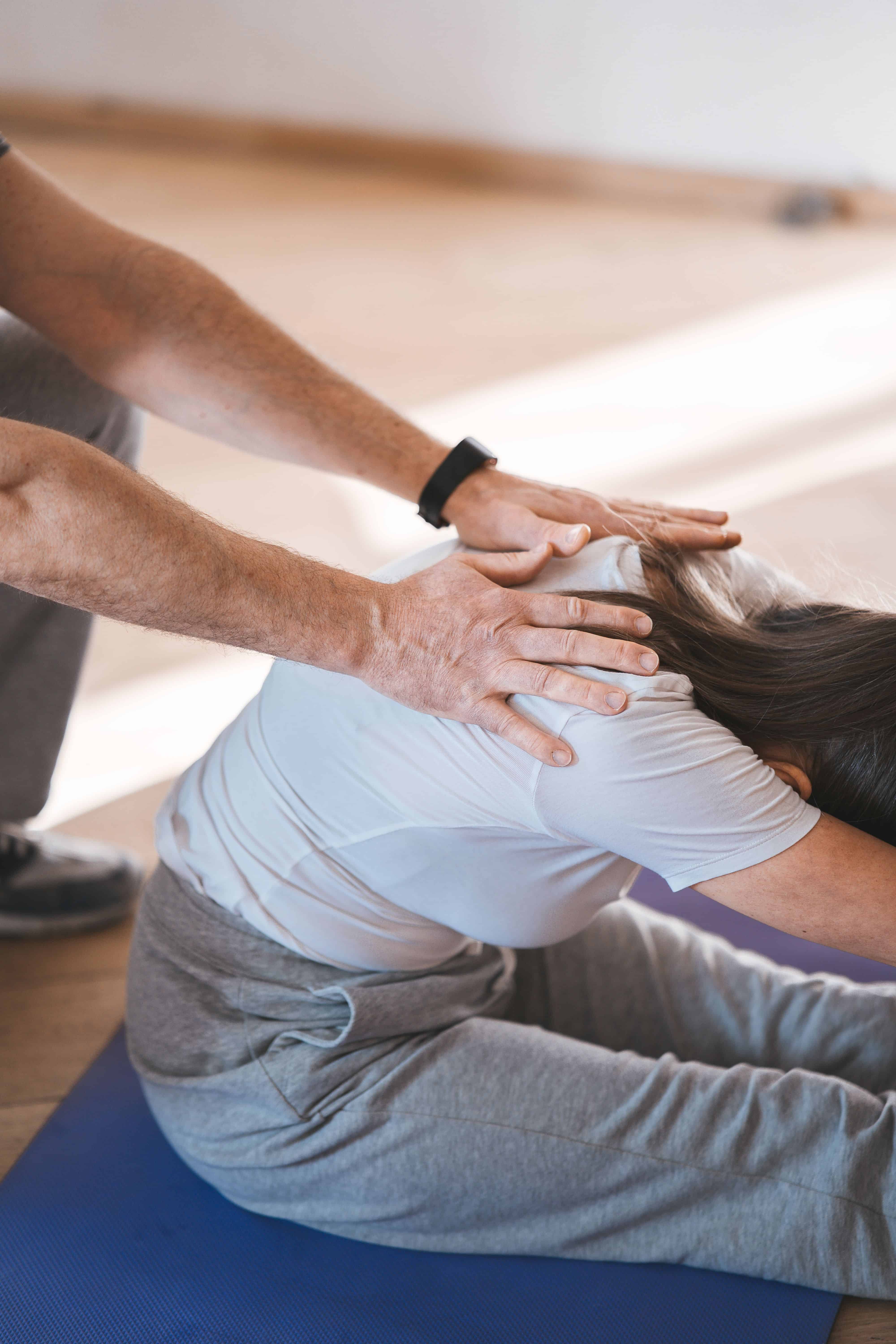 Fizjoterapeuta z Centrum Villa Medica we Wrocławiu pomaga pacjentowi leżącemu w ćwiczeniu rozciągającym kręgosłup